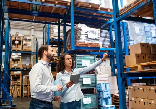 A female warehouse manager helping direct another employee using information gathered from a Dimensional Scanner